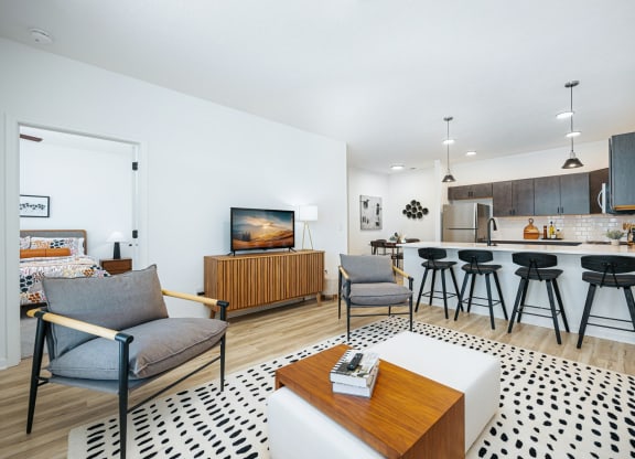 a living room with a kitchen and a bar with stools