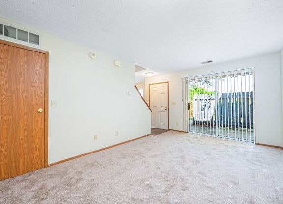 an empty living room with a door to a balcony