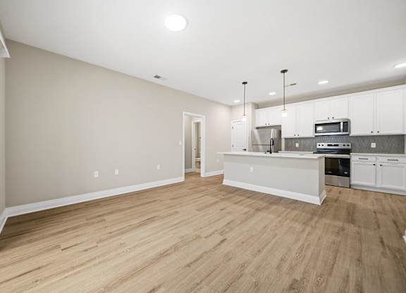 A kitchen with white cabinets and a wooden floor.