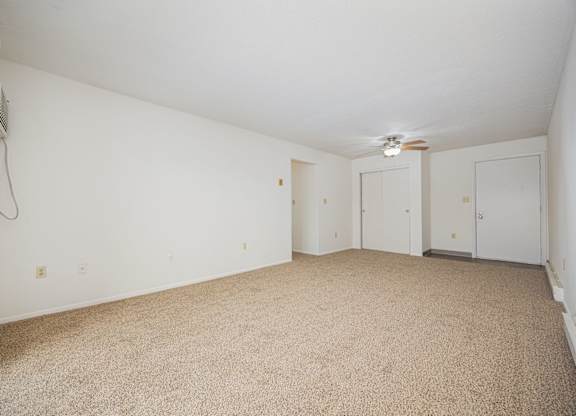 A room with carpeted floor and a ceiling fan.