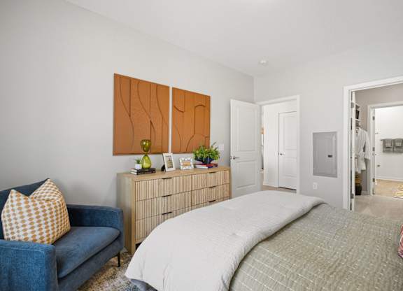 A bedroom with a bed, a couch, and a dresser.