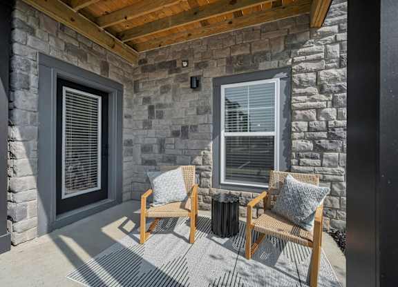 A patio with a wooden bench and a stone wall.
