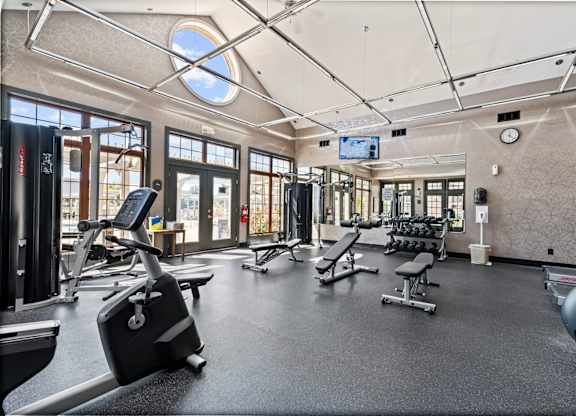 A gym with a variety of equipment including treadmills, weights, and exercise machines.