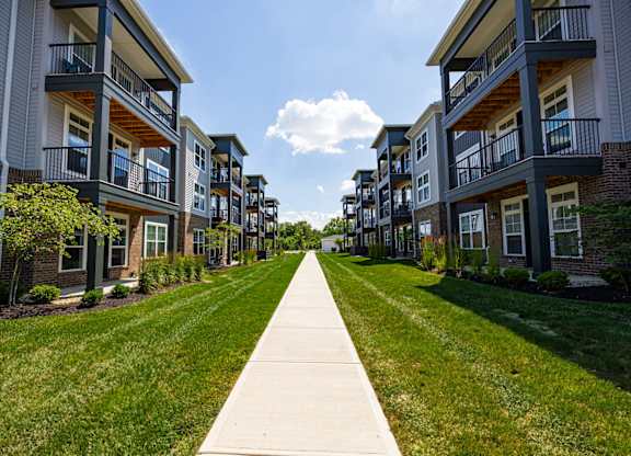 A long concrete walkway separates two rows of apartment buildings.