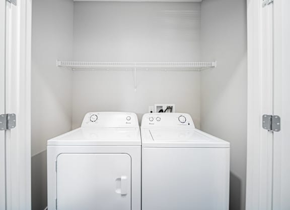 Two white washing machines in a small laundry room.