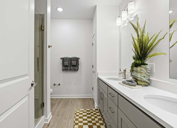 A bathroom with a white sink and a plant in a vase.
