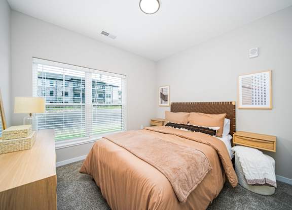 A bedroom with a bed, nightstand, and window.