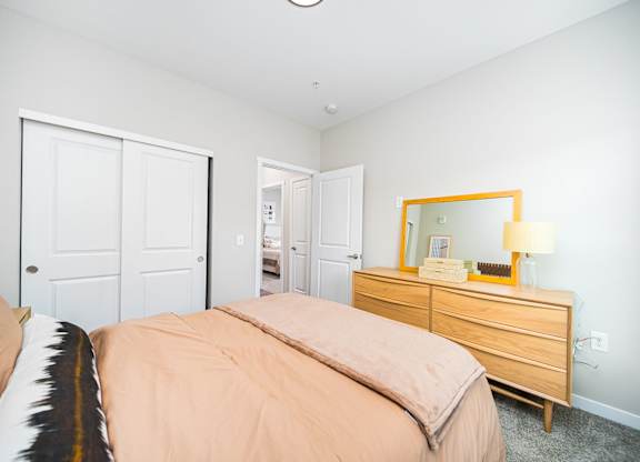 A bedroom with a bed, dresser, and mirror.