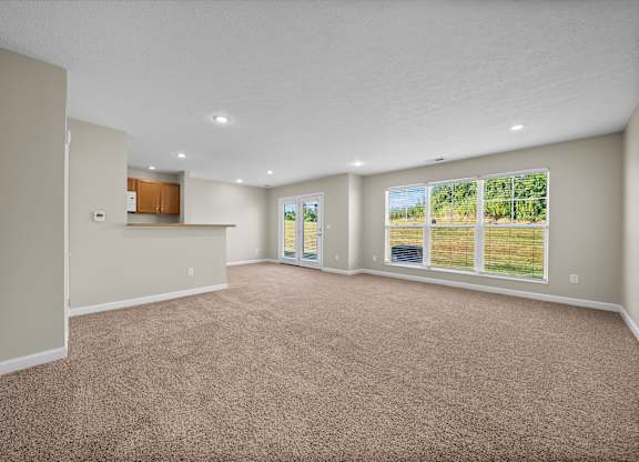 A spacious room with carpeted floor and large windows.