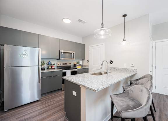A modern kitchen with a refrigerator, microwave, and sink.