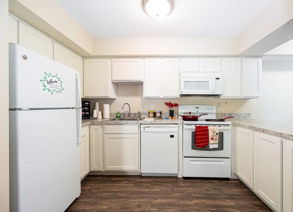 a kitchen with white cabinets and appliances and a white refrigerator