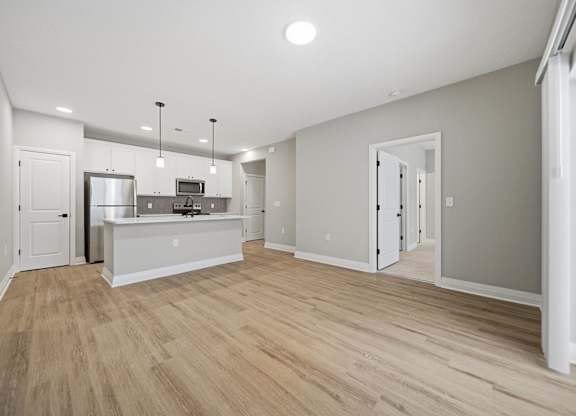 A kitchen with a refrigerator, microwave, and oven.