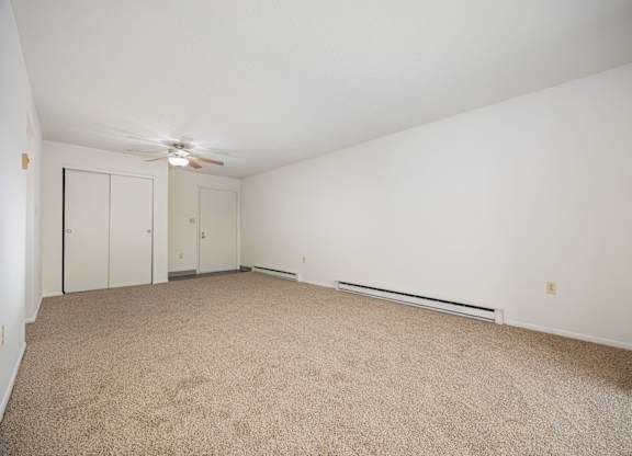 A room with a carpet floor and a ceiling fan.