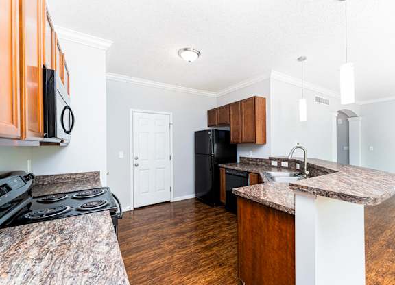 A kitchen with a black stove top oven and a black refrigerator.