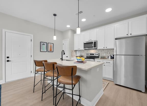 A kitchen with white cabinets and a stainless steel refrigerator.