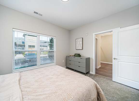 A bedroom with a bed, dresser, and window.