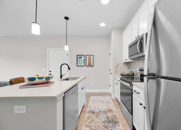 A modern kitchen with a white countertop and stainless steel appliances.