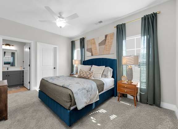 A bedroom with a large bed and a ceiling fan.