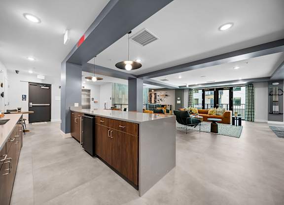 A modern kitchen with a large island and a living area with a couch and chairs.