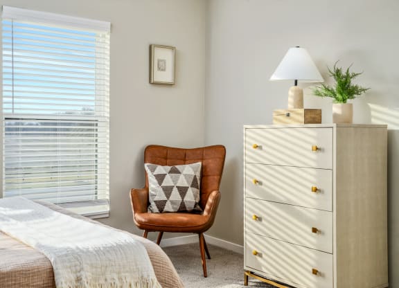 a bedroom with a bed and a chair and a dresser