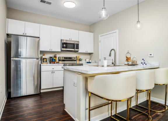 a kitchen with white cabinets and a counter top and a stainless steel refrigerator