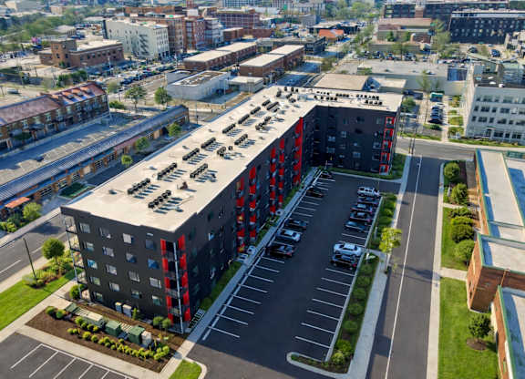 A parking lot is in front of a large building with a red and black facade.