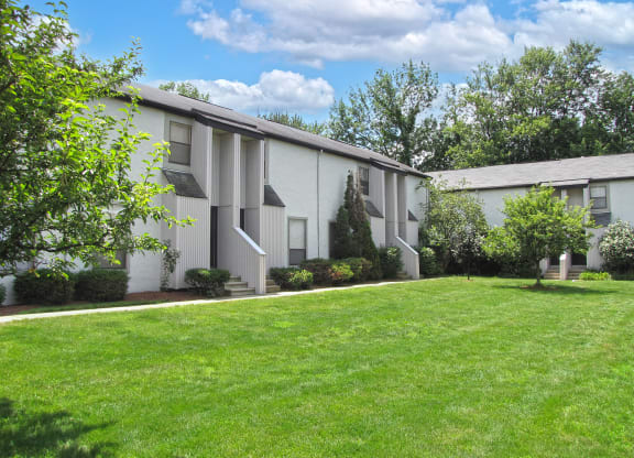 a white apartment building with a green lawn and trees