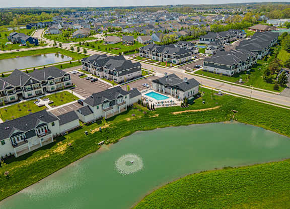 A bird's eye view of a residential area with houses and a pond.