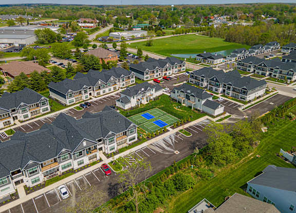 A bird's eye view of a residential area with houses, cars, and a tennis court.