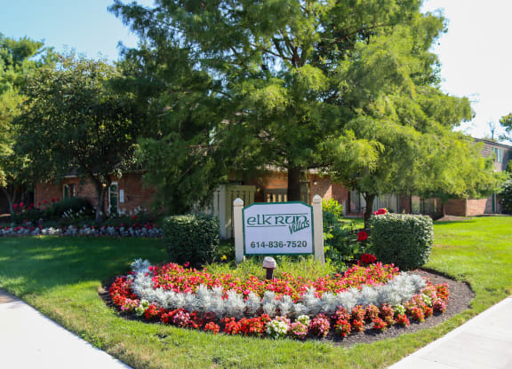 a flower bed in front of a sign for a city street