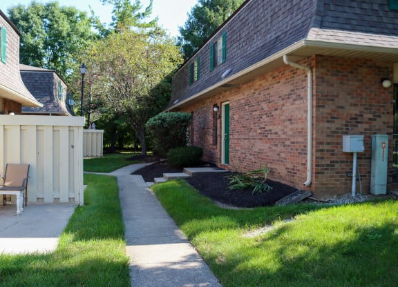 a walkway in front of a brick house with a yard and a patio