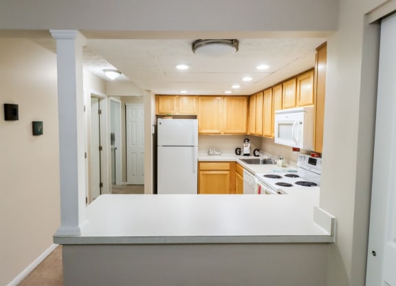 an empty kitchen with a white counter top and a refrigerator
