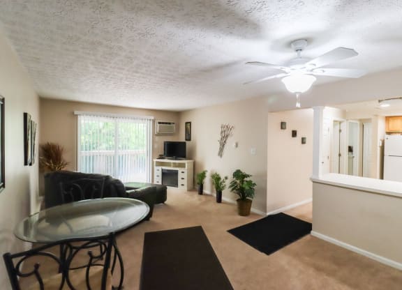an open living room with a kitchen and a ceiling fan