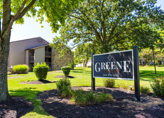 a sign that says greene apartments with a building in the background