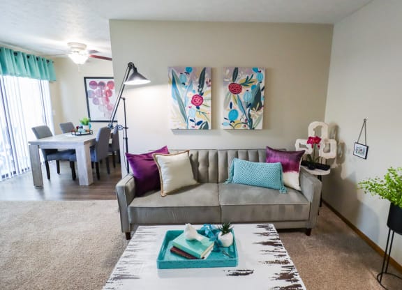 A living room with a grey couch, a white coffee table, and a painting on the wall.