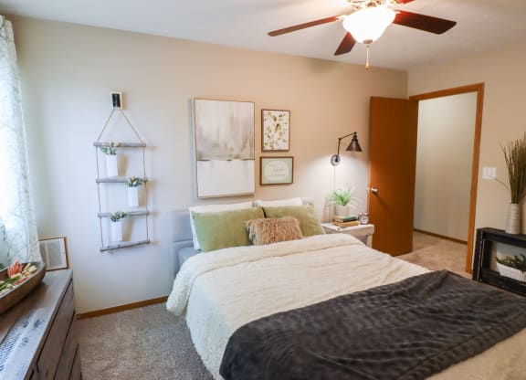 A bedroom with a bed, a window, and a ceiling fan.