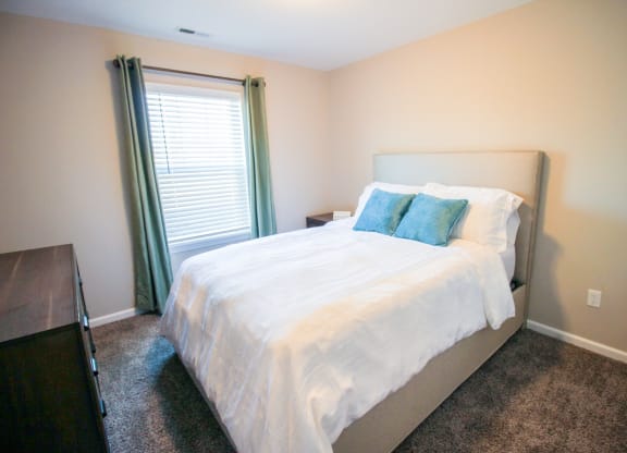 a bedroom with white bedding and green pillows