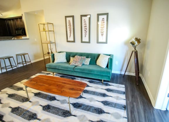 a living room with a green couch and a cowhide rug