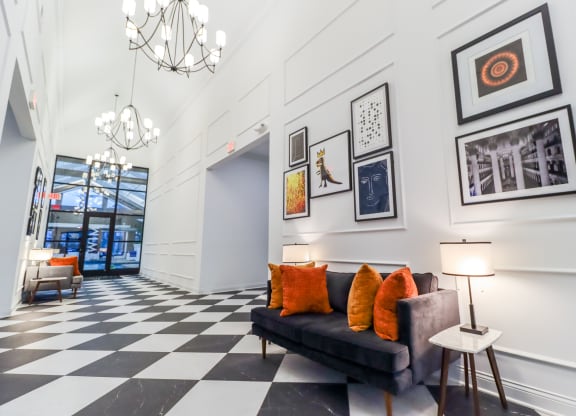 a lobby with a black and white checkered floor and a couch with orange pillows