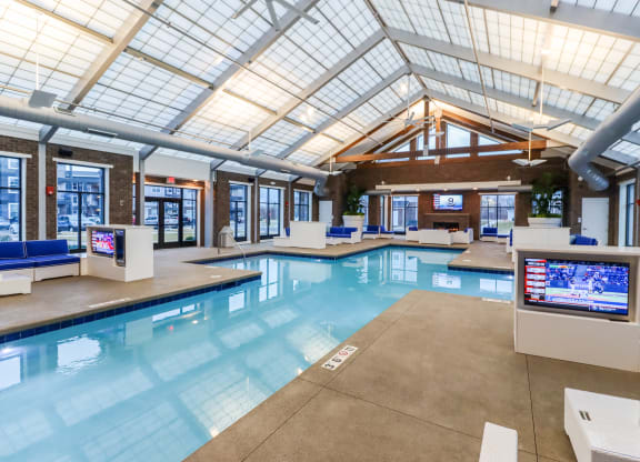 a large indoor pool with a skylight and televisions