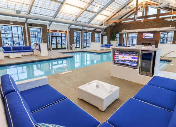 a large indoor pool with blue lounge chairs and a white coffee table