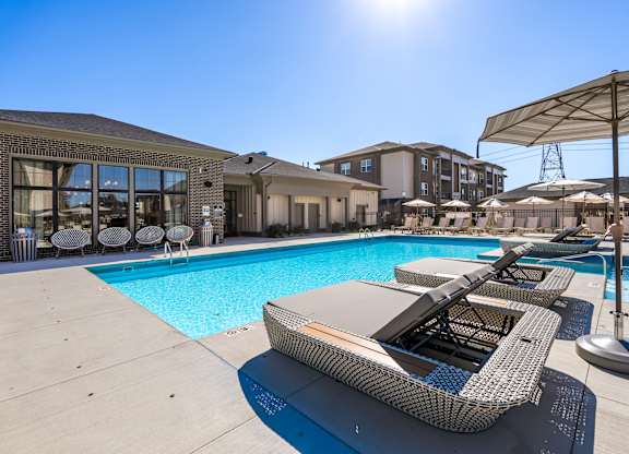 A sunny day at the pool with a sun lounger in the foreground.