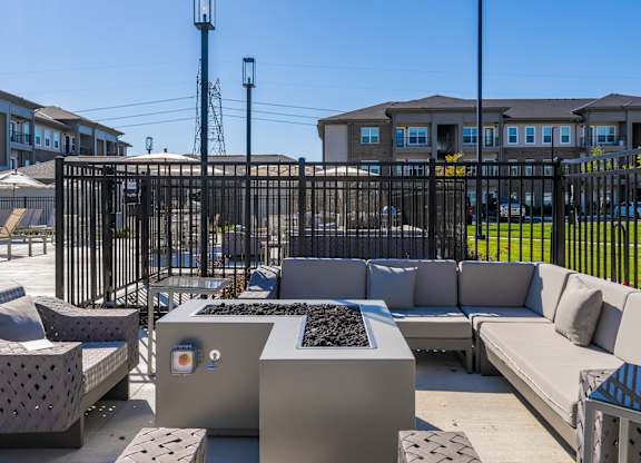A black metal fence surrounds a concrete patio with a bench and a table.