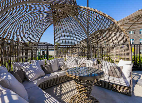 A patio with a wicker table and chairs under a canopy.
