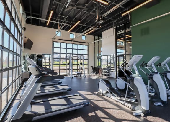 a gym with cardio equipment and windows in a building