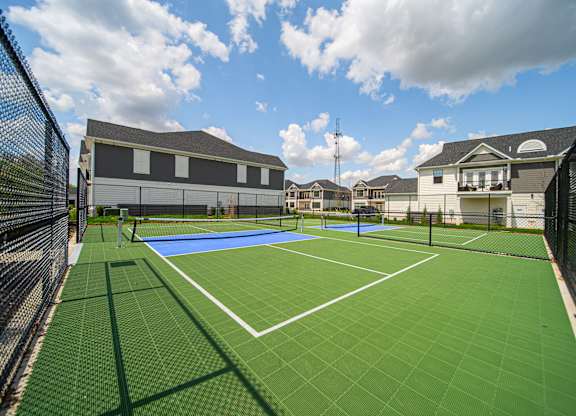 A tennis court surrounded by a black fence.
