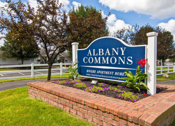 the sign commons in front of a brick retaining wall with flowers
