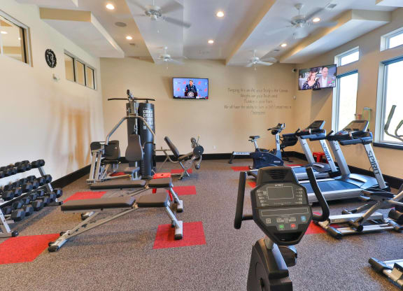 a gym with exercise equipment and a tv on the wall