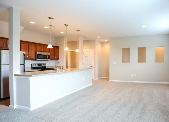 an empty living room and kitchen with a counter top