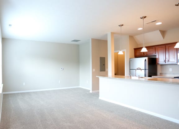 an empty living room and kitchen with a counter top